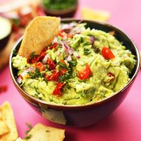 Dipping a tortilla chip into a bowl of Greek Guacamole