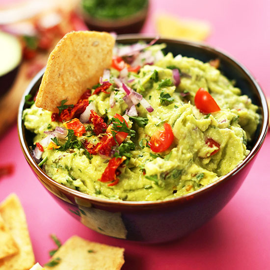 Dipping a tortilla chip into a bowl of Greek Guacamole