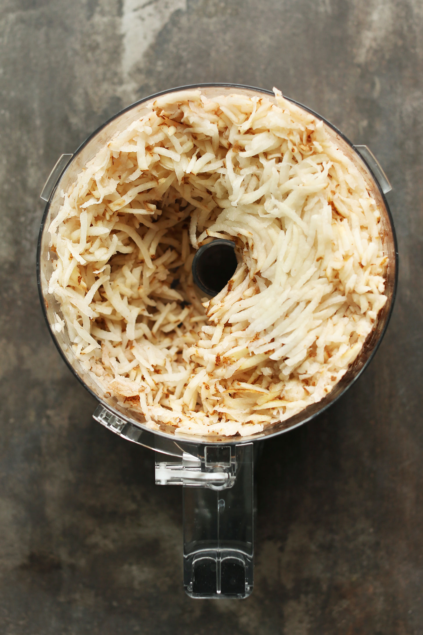 Food processor with grated potatoes for making into delicious crispy hashbrowns