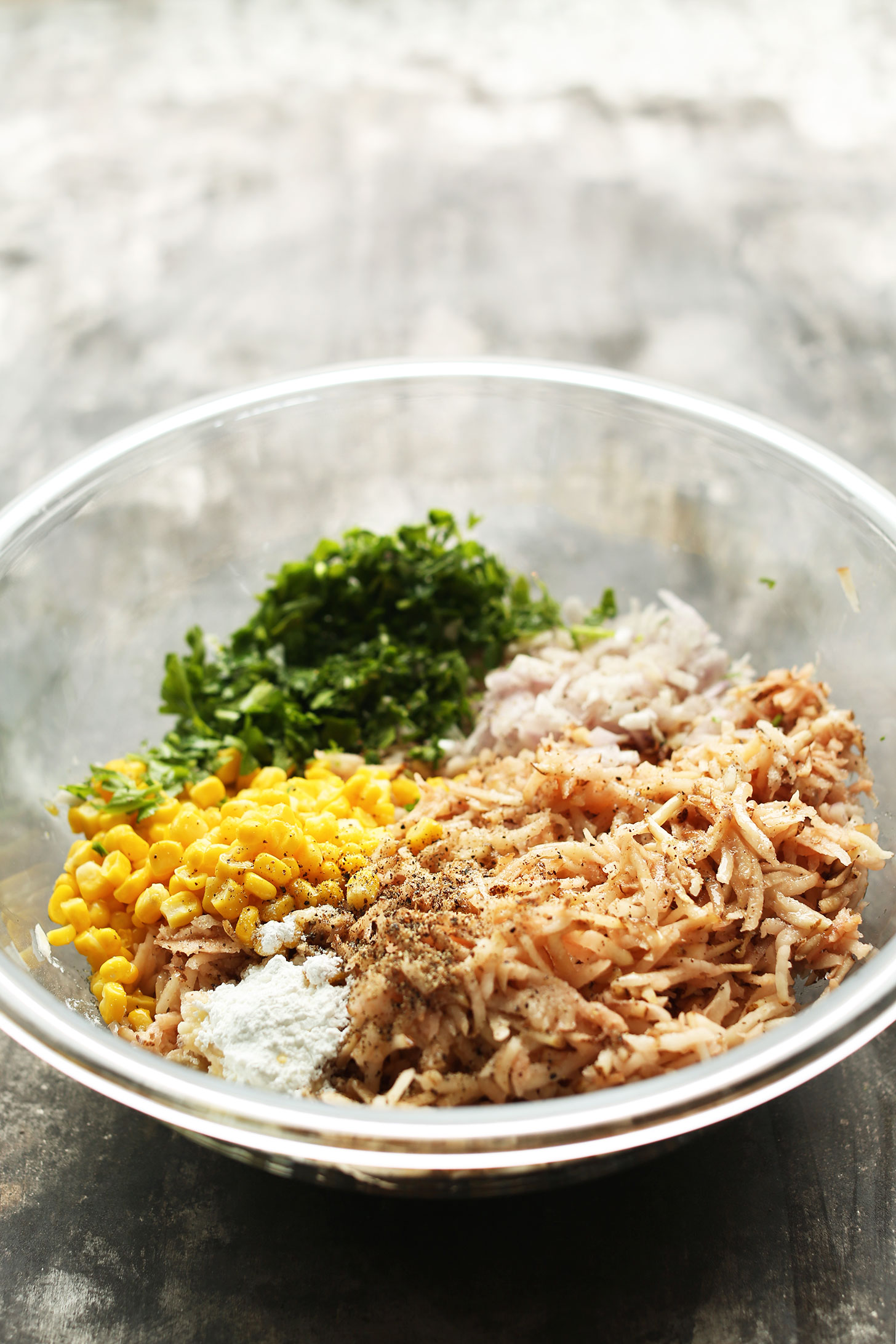 Mixing bowl with ingredients for making Crispy Hash Browns with corn, parsley, and shallot