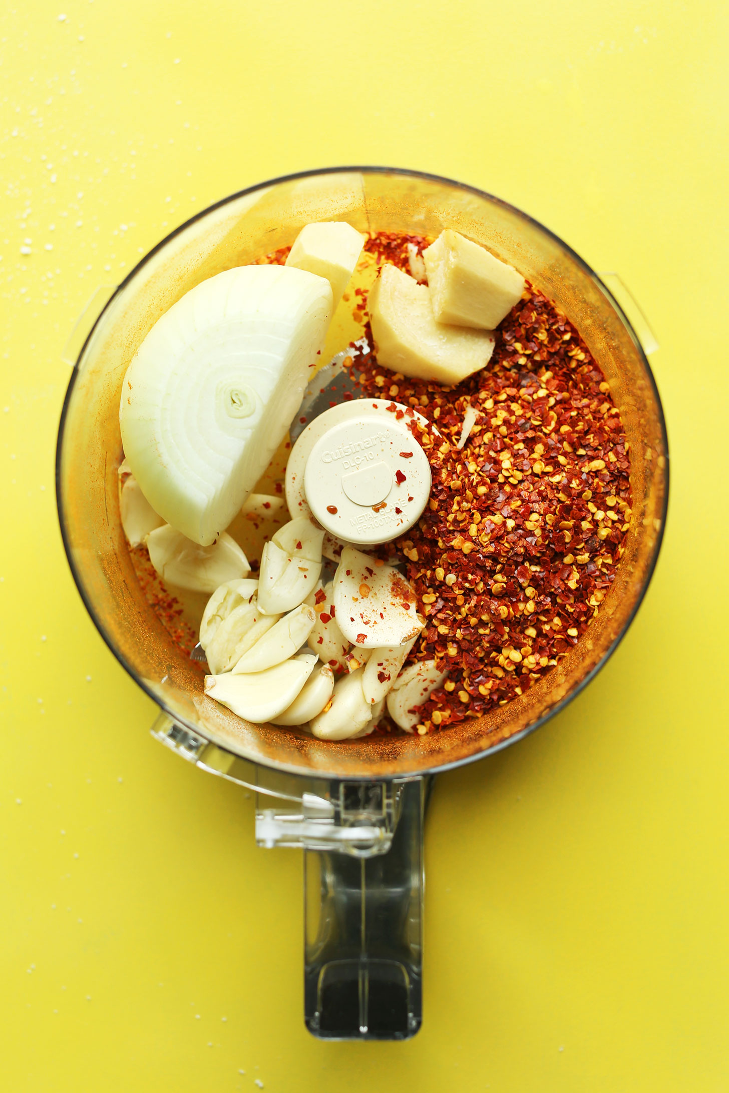 Food processor with onion, garlic, and spices for making our easy vegan kimchi recipe