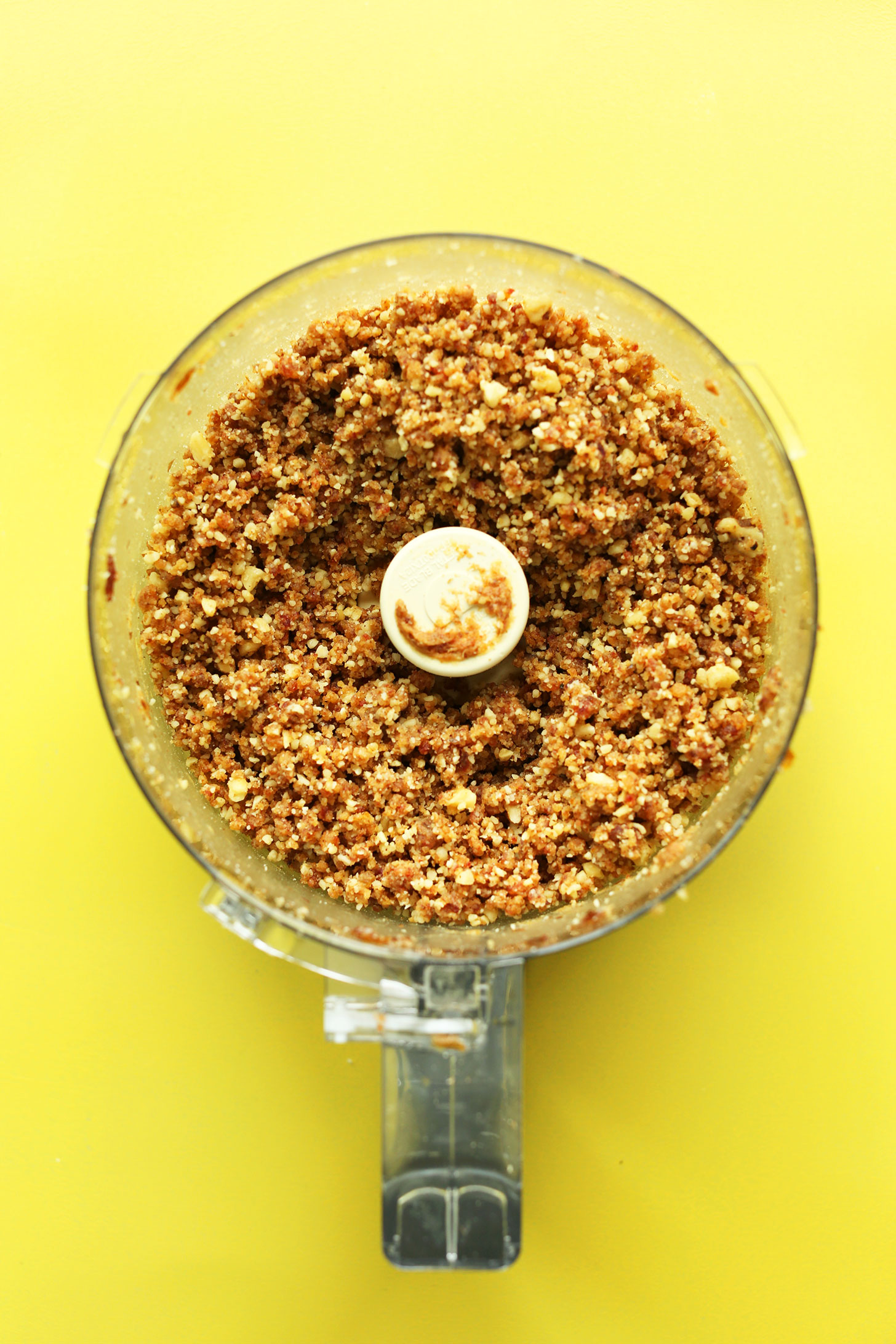 Food processor with ingredients for making the date and walnut crust for our vegan cheesecake