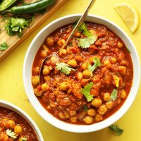 Big bowl of Vegan Chana Masala alongside a cutting board of serranos and cilantro