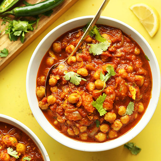 Big bowl of Vegan Chana Masala alongside a cutting board of serranos and cilantro