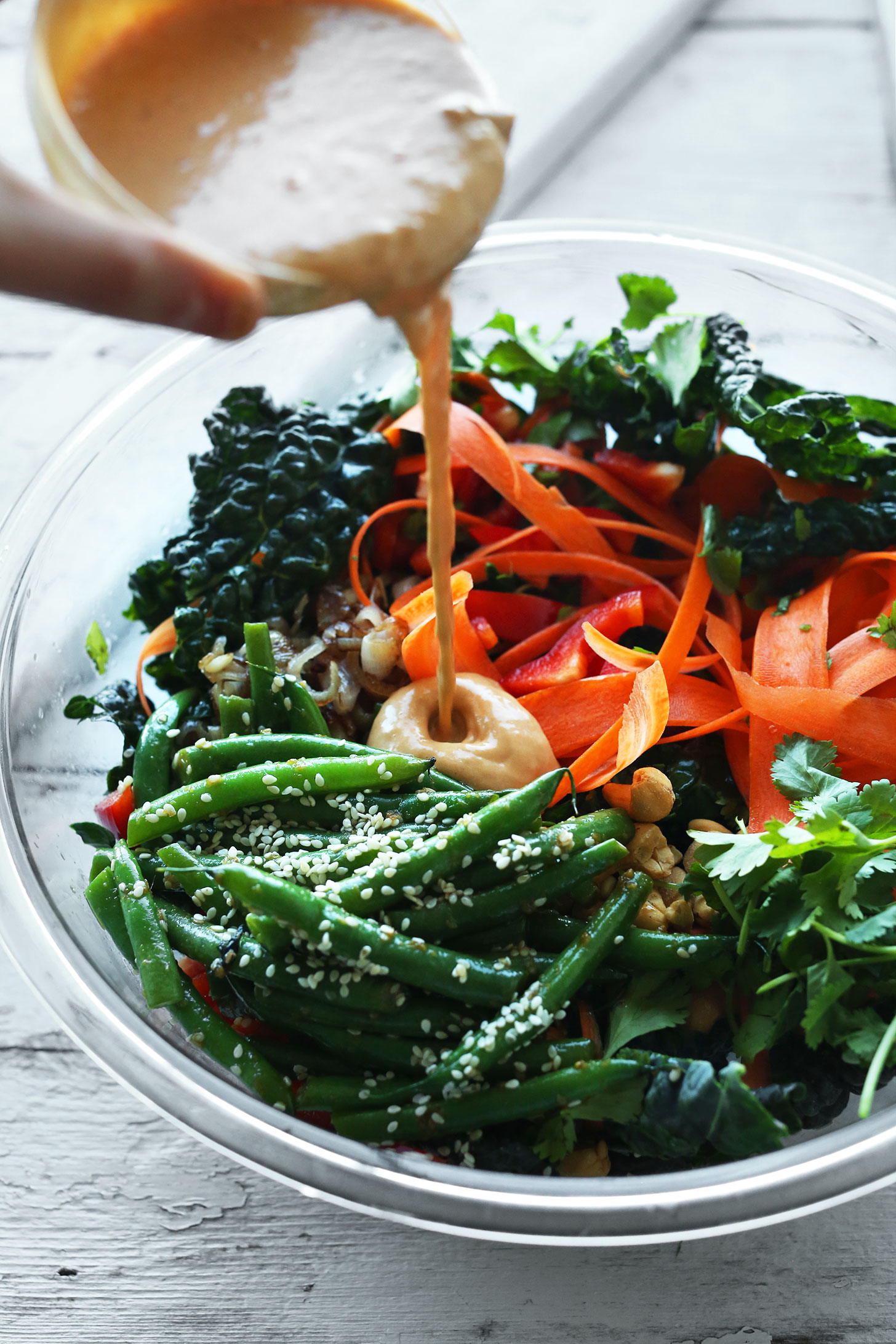 Pouring homemade gingery Cashew Dressing onto our Thai Kale Salad recipe