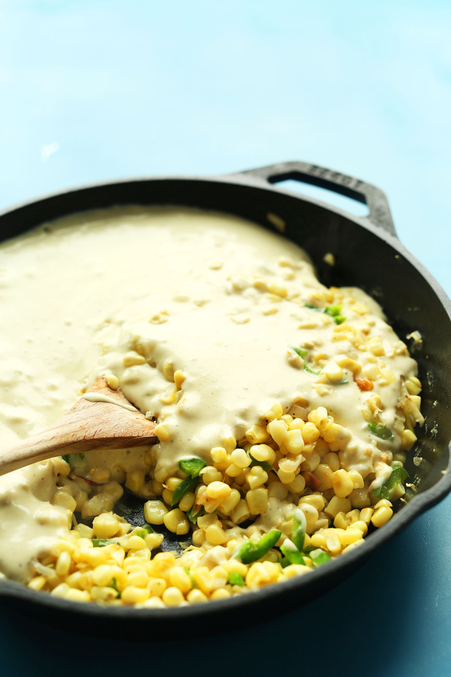 Making Cheesy Vegan Corn Dip with Jalapenos in a cast-iron skillet