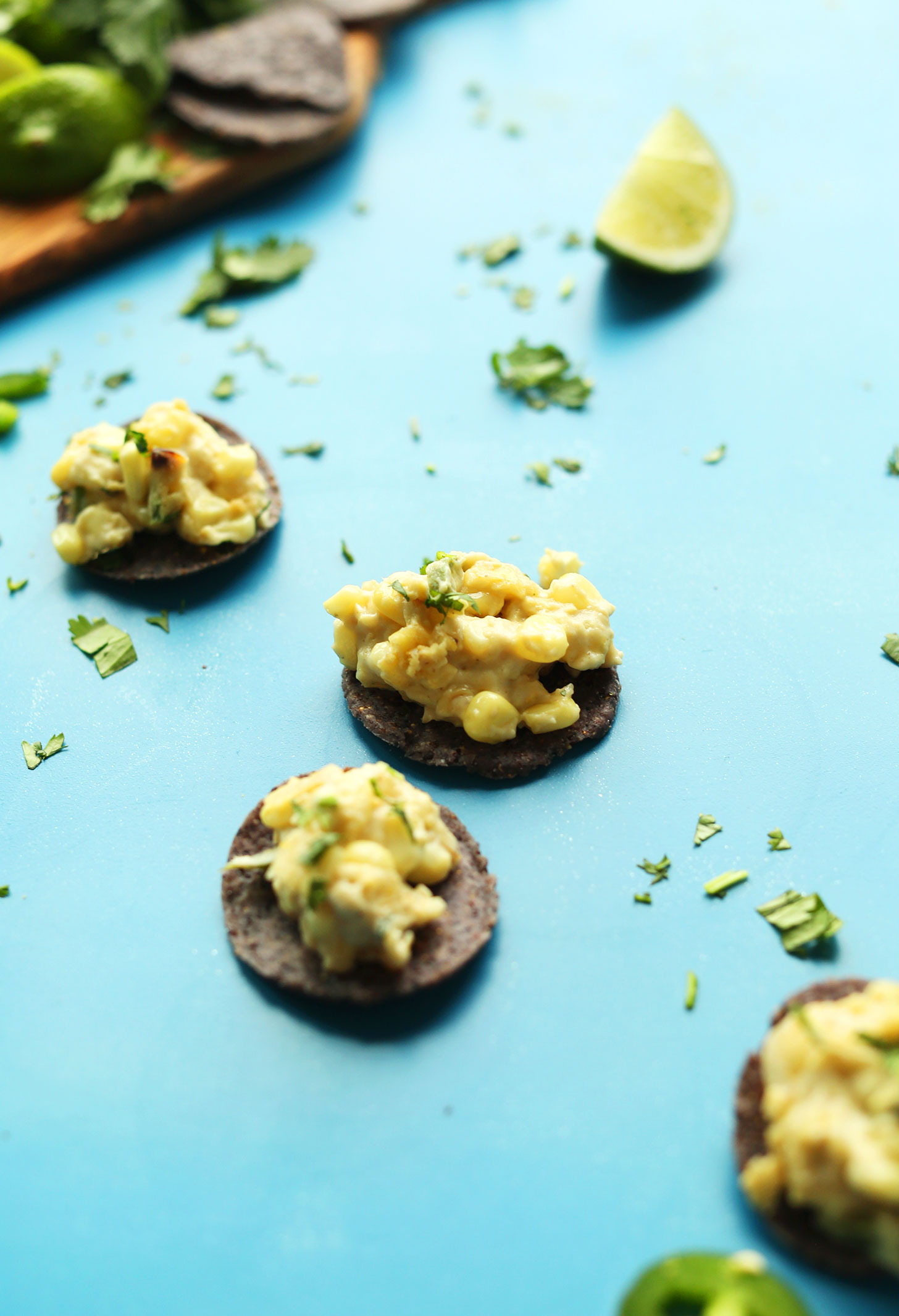 Round blue corn chips topped with creamy vegan Corn Dip with Jalapenos