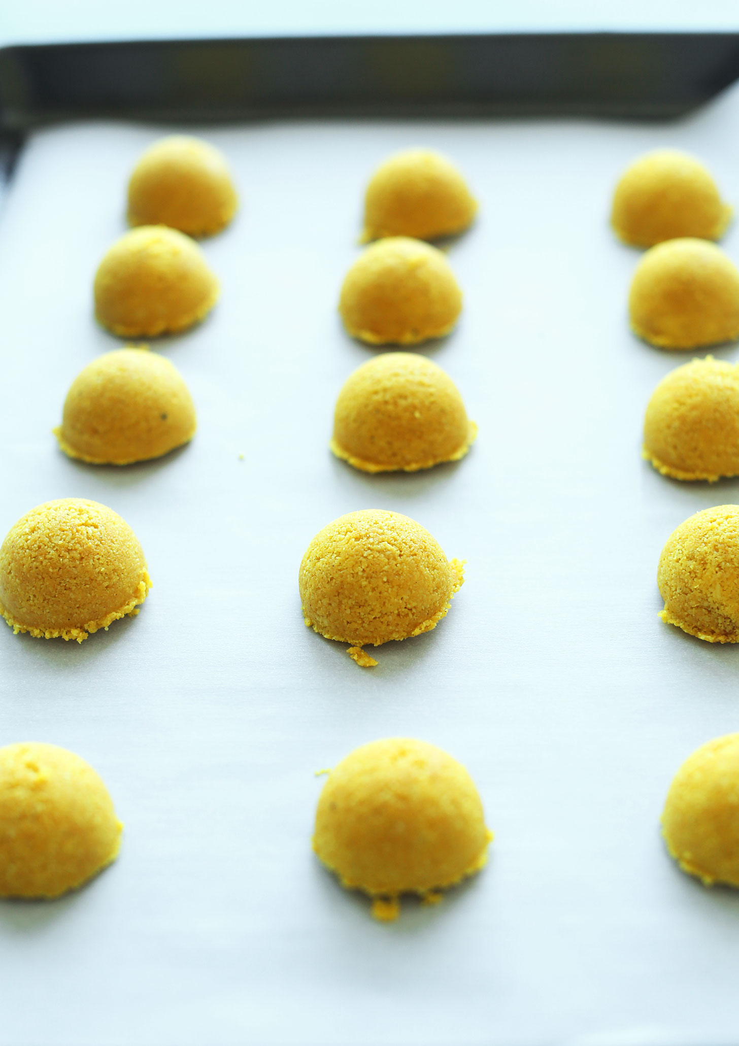 Parchment-lined baking sheet with perfect mounds of our Golden Milk Macaroons recipe