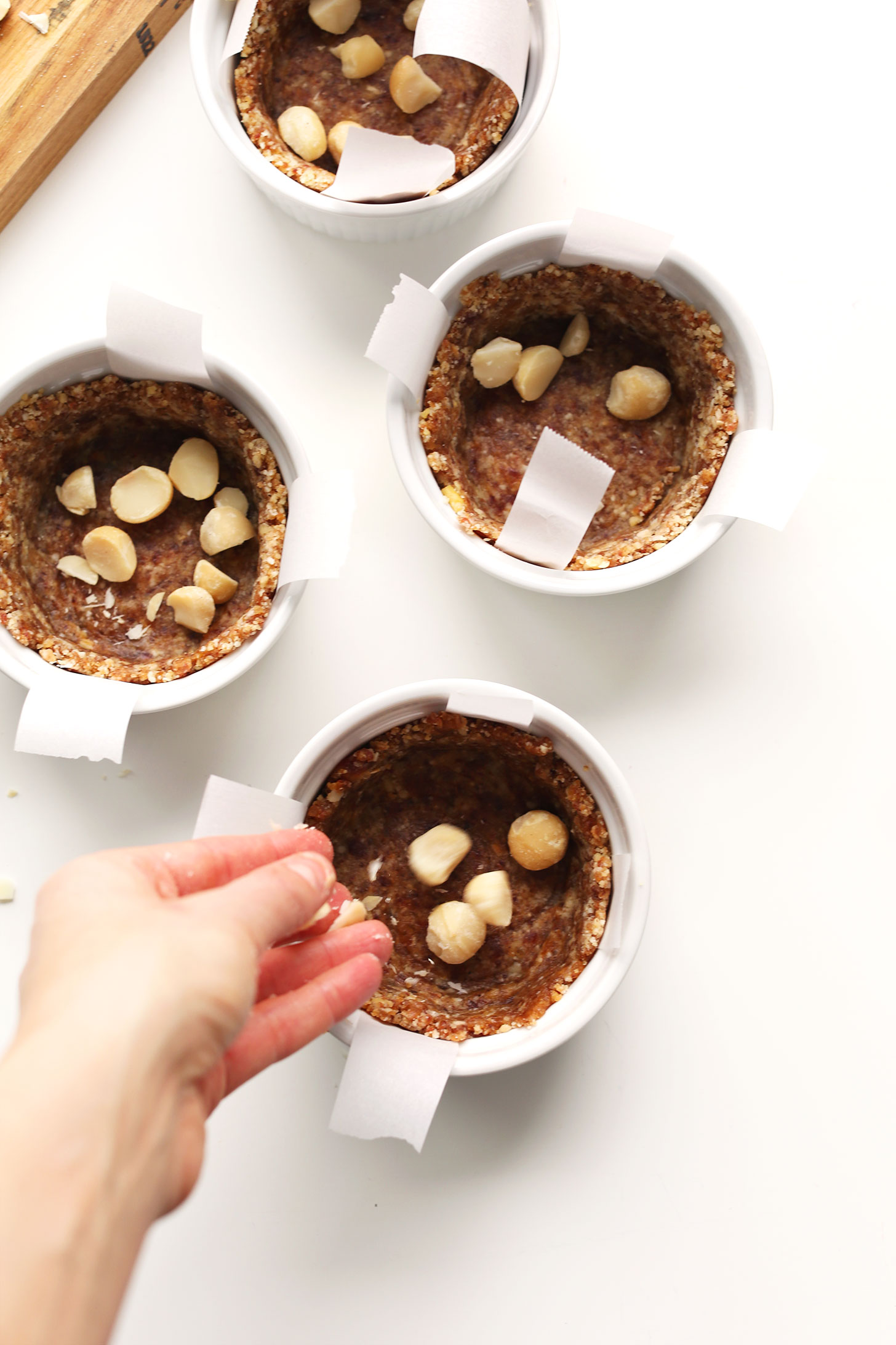 Ramekins fileld with crust and macadamia nuts for making mini gluten-free vegan cheesecakes