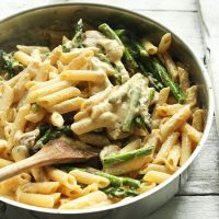 Wooden spoon in a skillet of Creamy Vegan Mushroom Asparagus Pasta