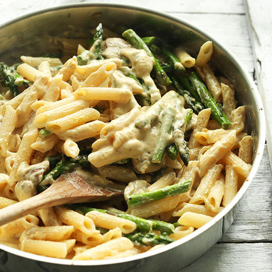 Wooden spoon in a skillet of Creamy Vegan Mushroom Asparagus Pasta