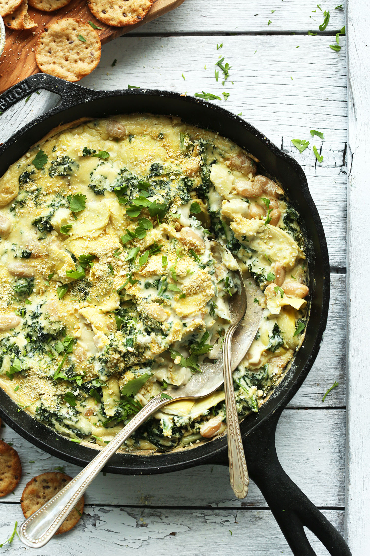 Cast-iron skillet filled with creamy gluten-free vegan Kale & White Bean Artichoke Dip