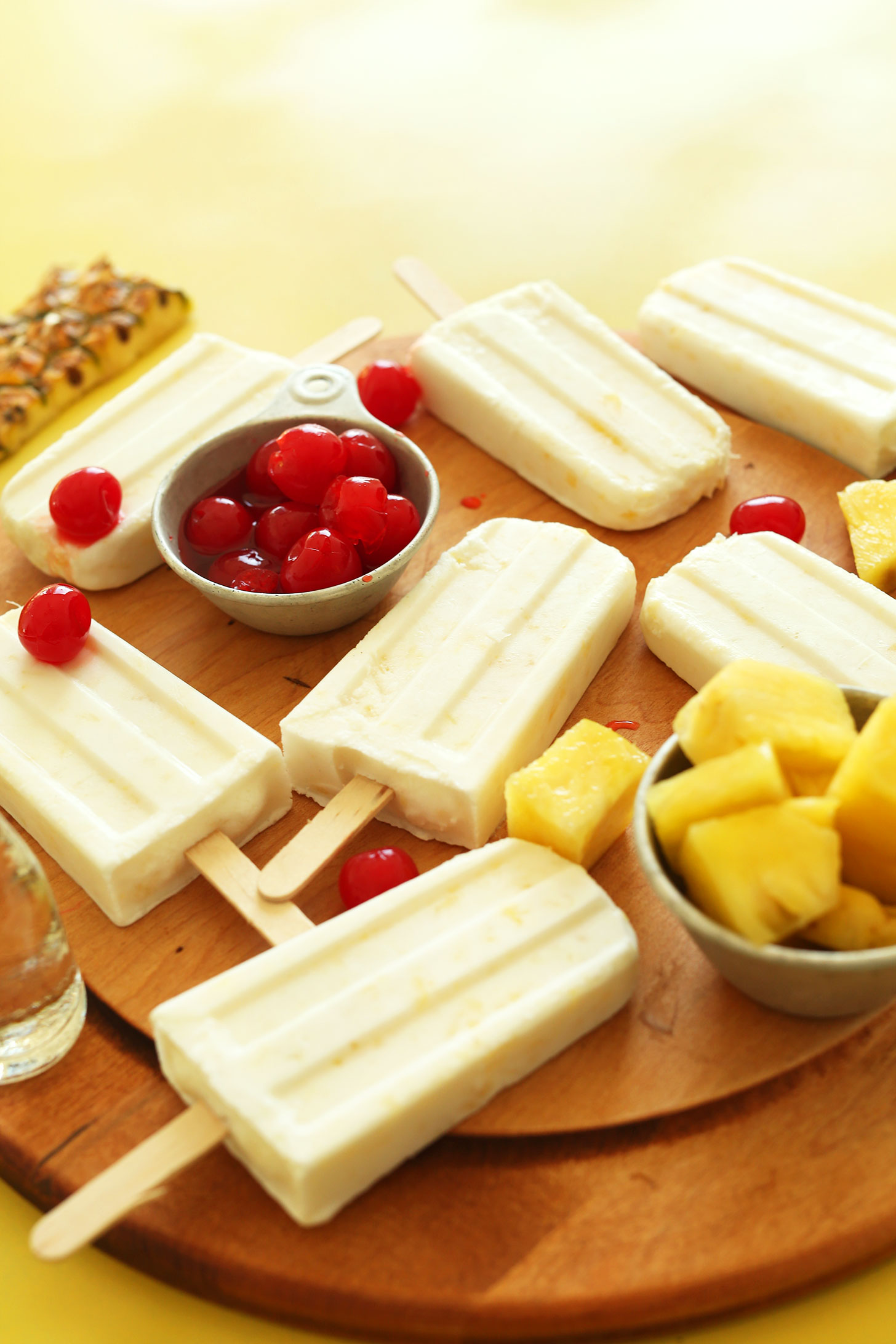 Homemade refreshing Pina Colada vegan Popsicles surrounded by fresh fruit