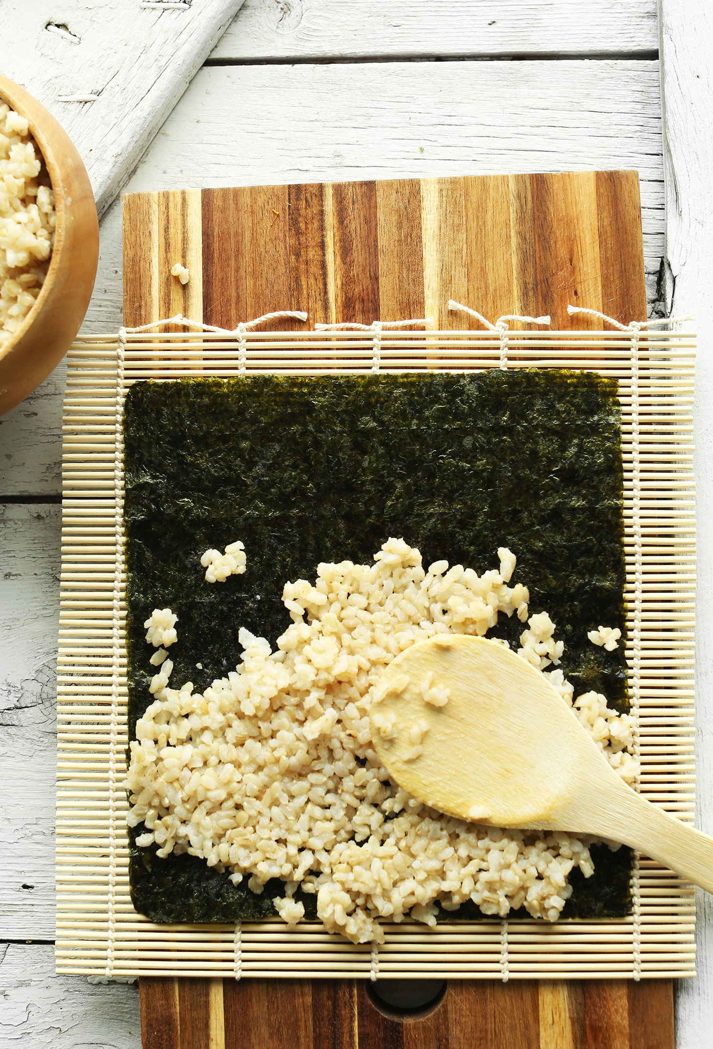 Spreading rice onto a sheet of nori for making homemade vegan sushi