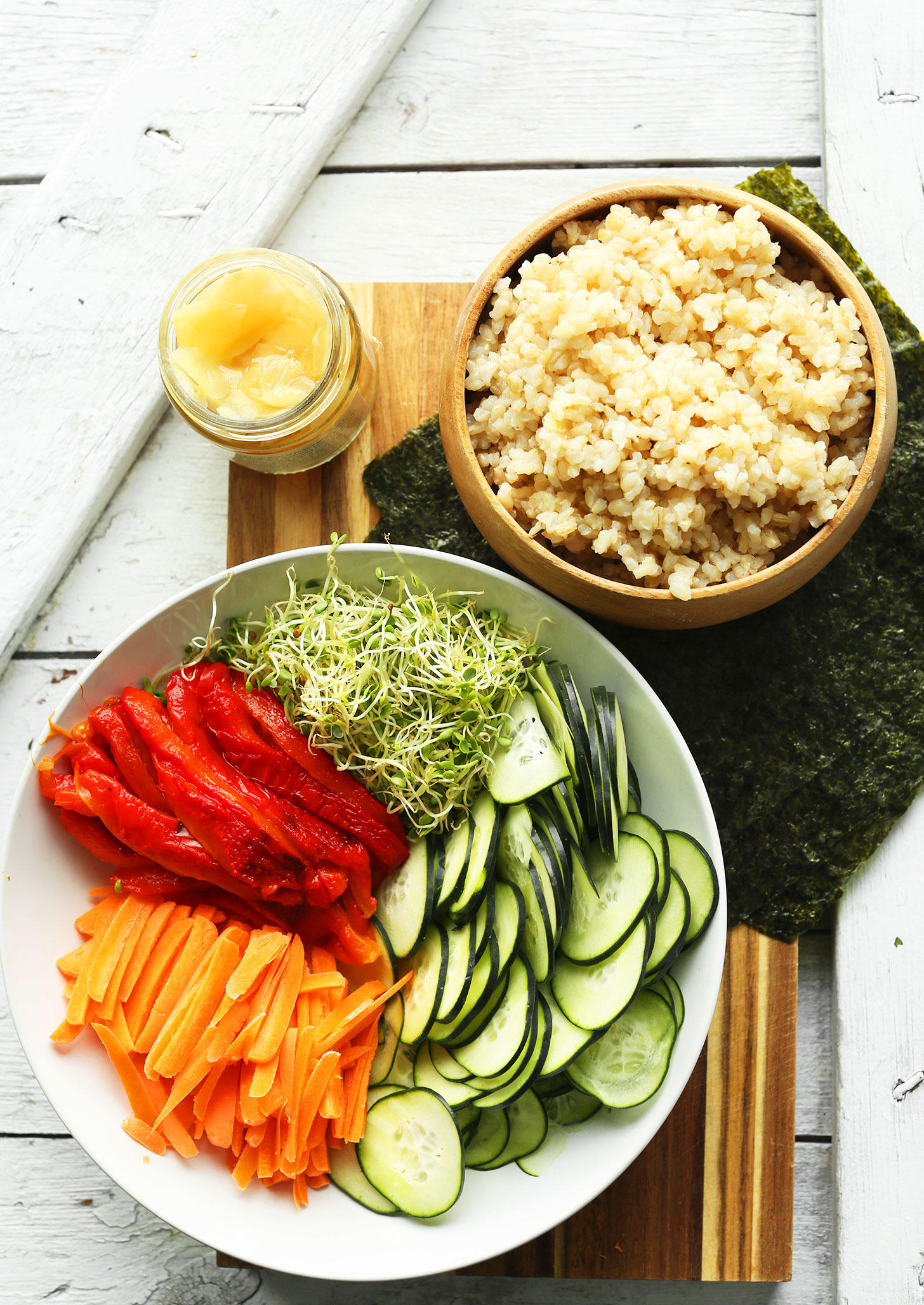 Sliced carrots, bell pepper, carrots, sprouts, ginger, and brown rice for making vegan sushi