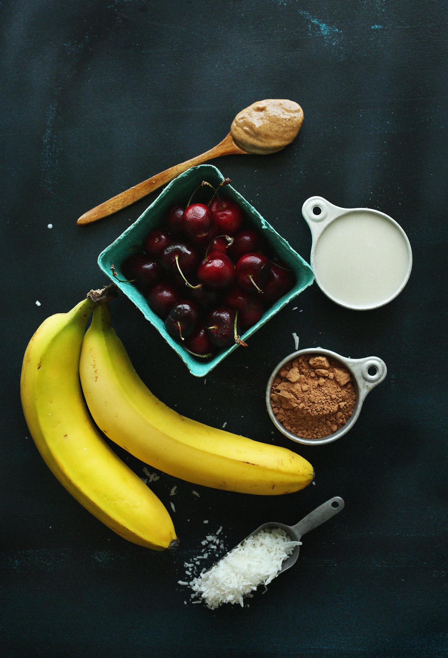 Nut butter, nut milk, cherries, bananas, cocoa powder, and shredded coconut for making our vegan Banana Split Smoothie