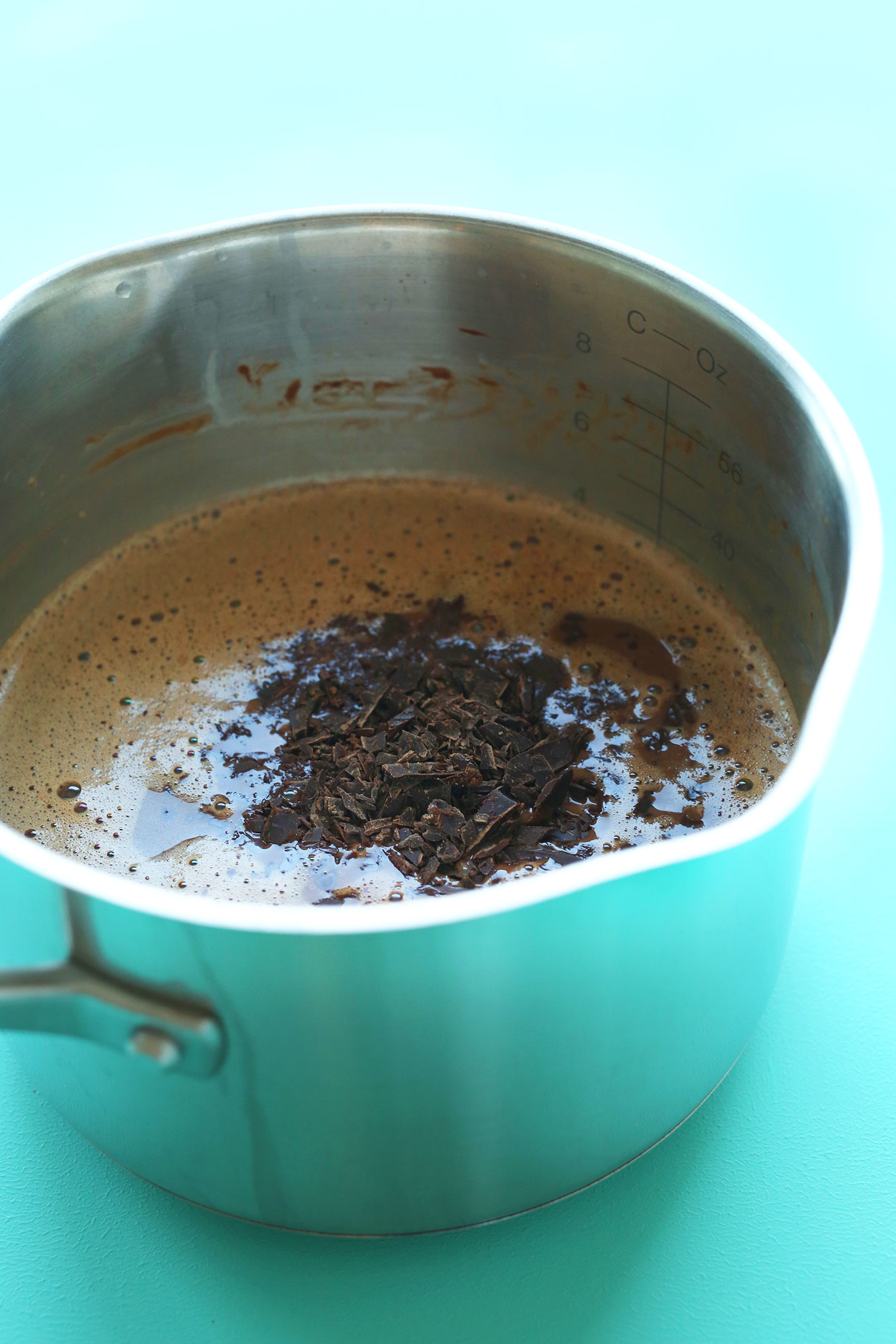 Adding chocolate shavings to a saucepan for homemade vegan chocolate ice cream
