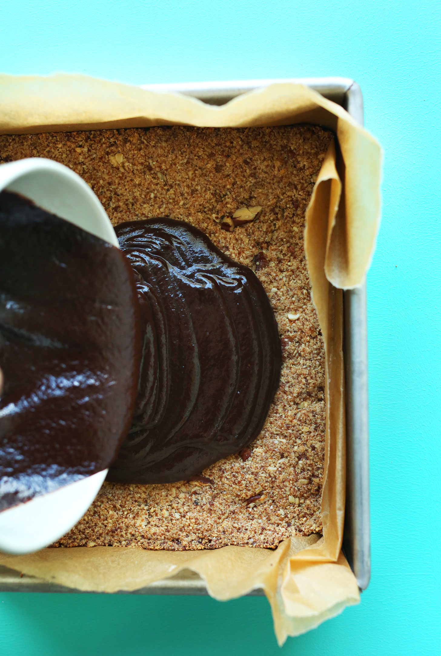 Pouring chocolate ganache over the crust for gluten-free vegan S'Mores Bars