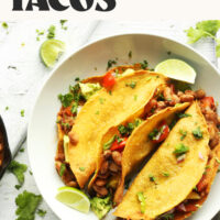 Text saying Crispy Vegan Baked Tacos with Pineapple Salsa above two bowls with tacos in them