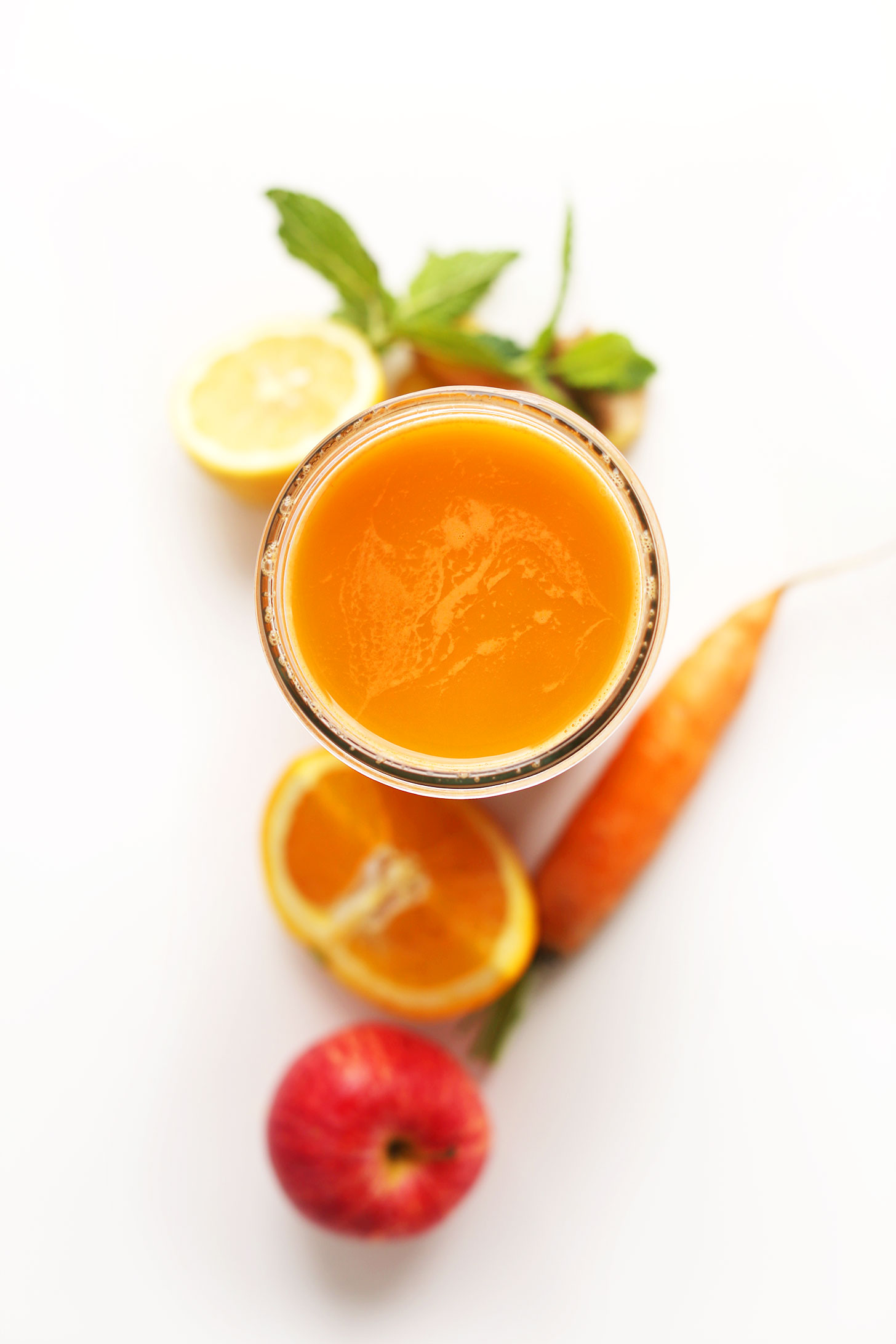 Mason jar filled with our Super-Powered Orange Juice recipe surrounded by ingredients for making it