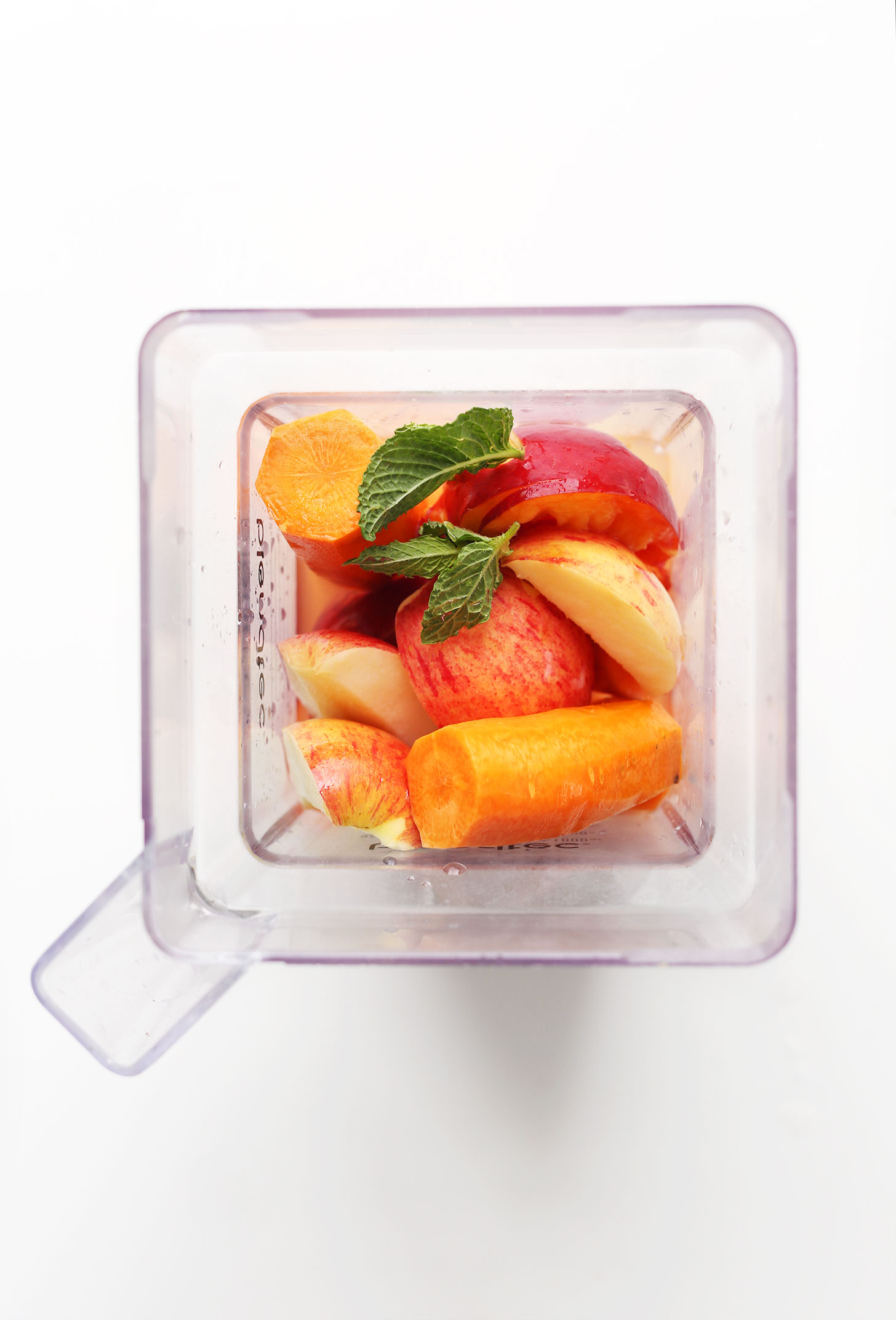 Blender filled with ingredients for making our Carrot Apple Nectarine Ginger Lemon Juice