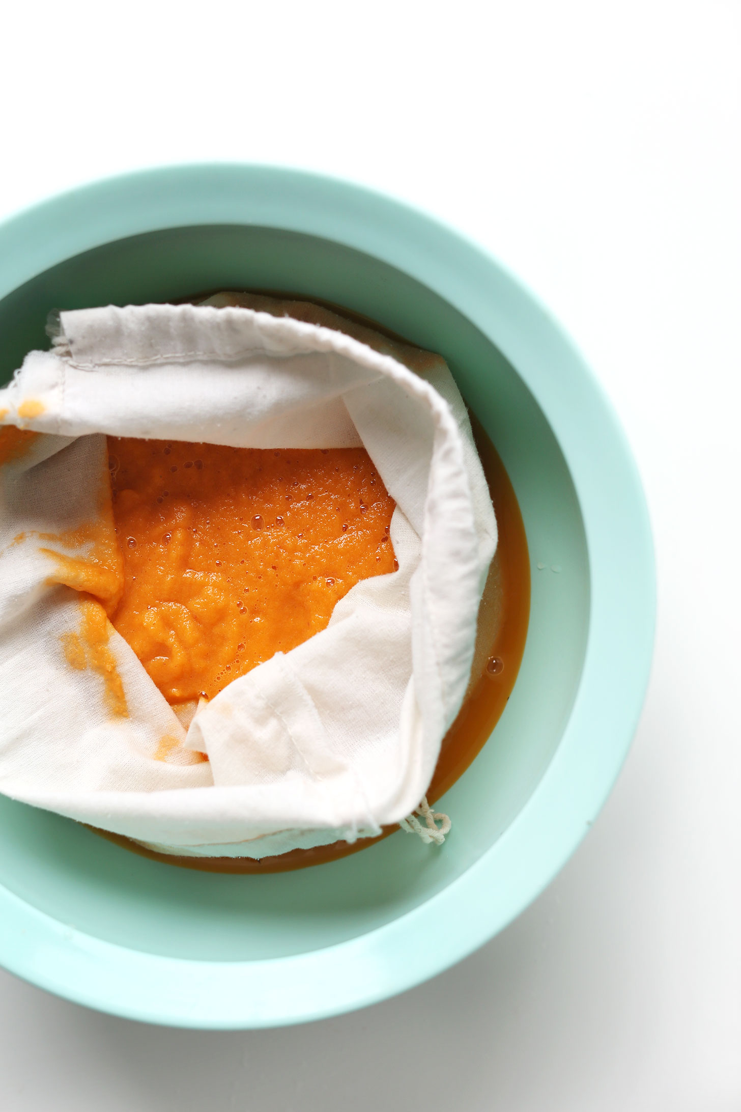 Straining our Super-Powered Orange Juice through a nut milk bag to remove the pulp