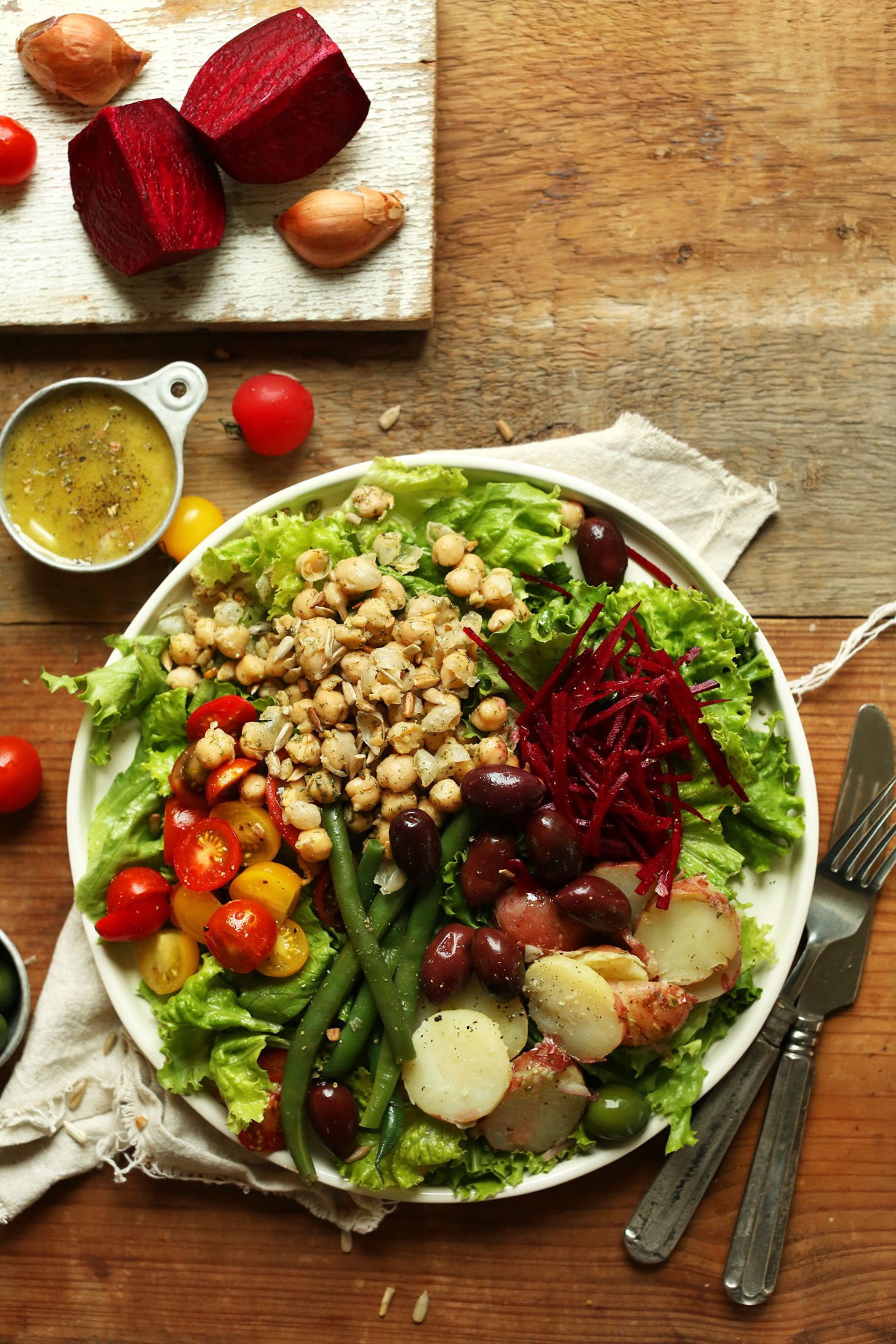 Big Vegan Nicoise Salad with lettuce, shredded beets, olives, green beans, potatoes, tomatoes, chickpeas, and dressing