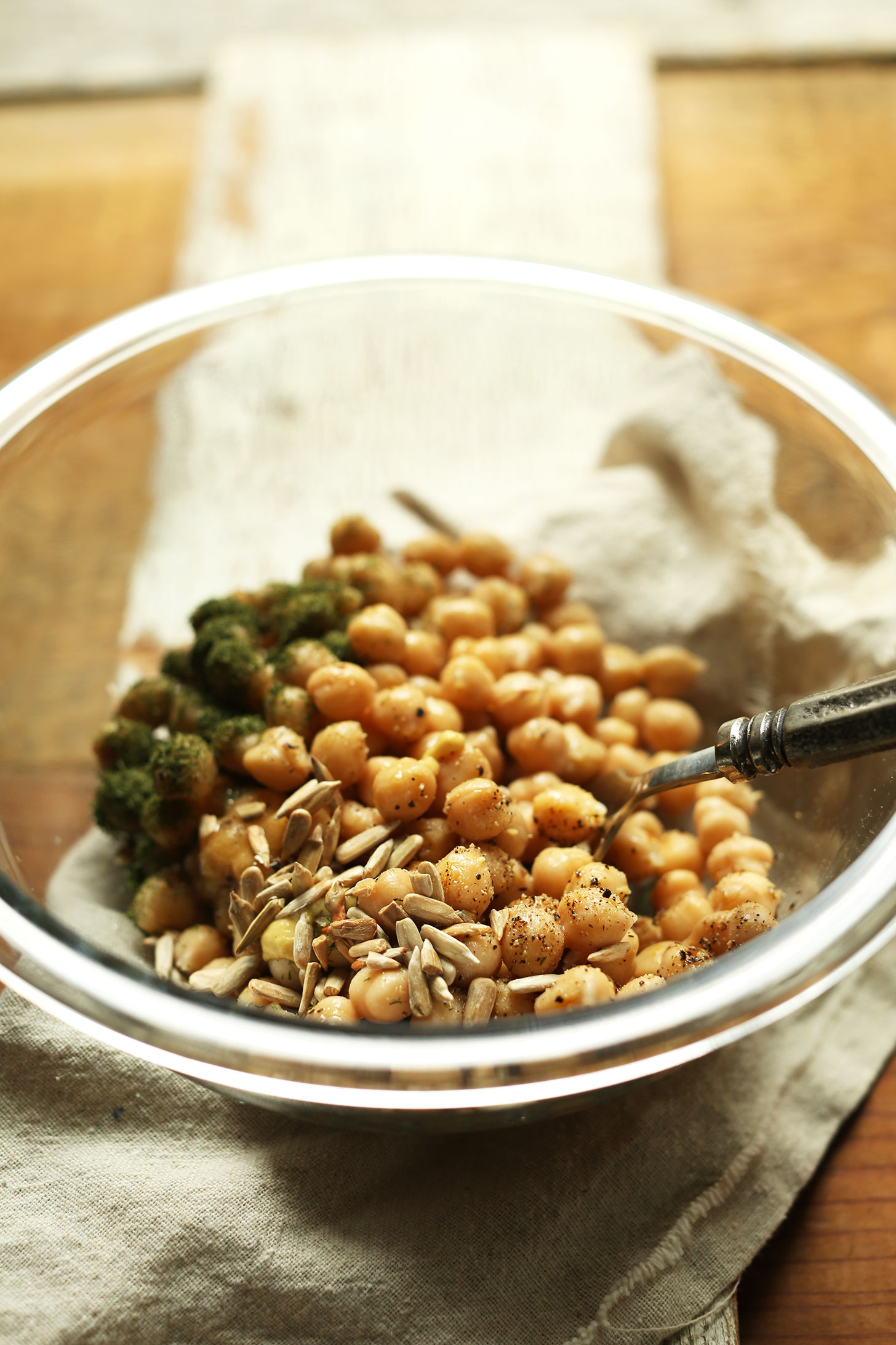 Stirring together chickpeas, sunflower seeds, and dill to make a vegan whole meal salad
