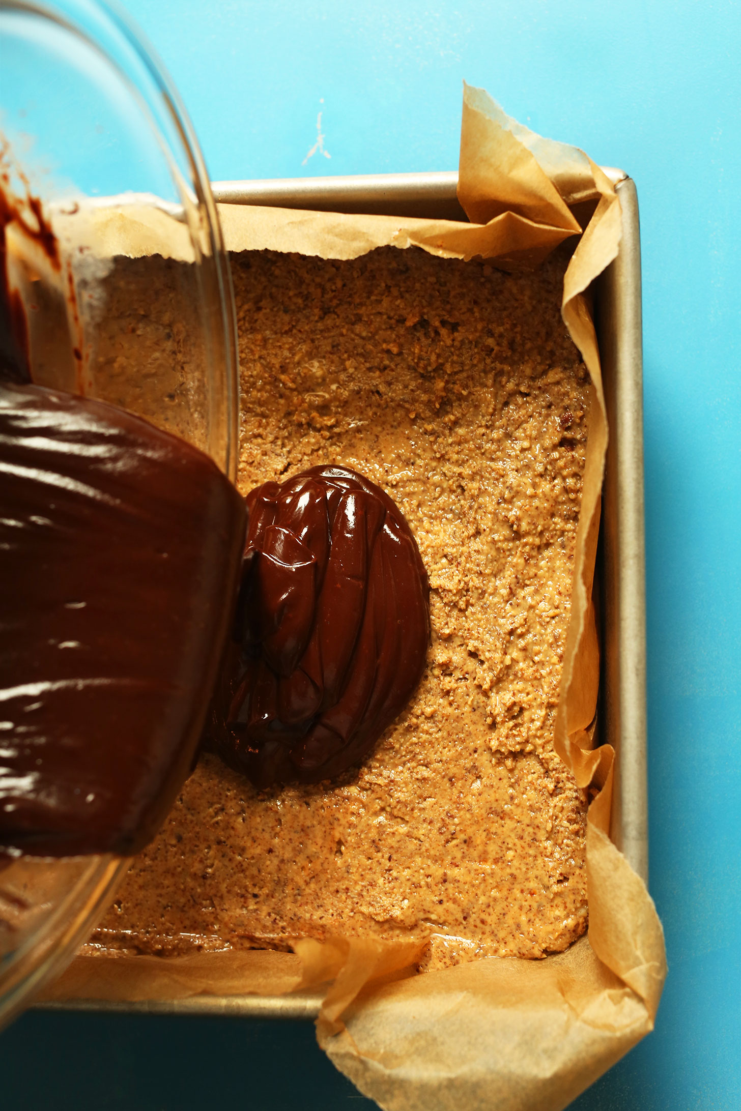 Pouring ganache layer of Almond Butter Cup Bars for making an easy and delicious dessert recipe