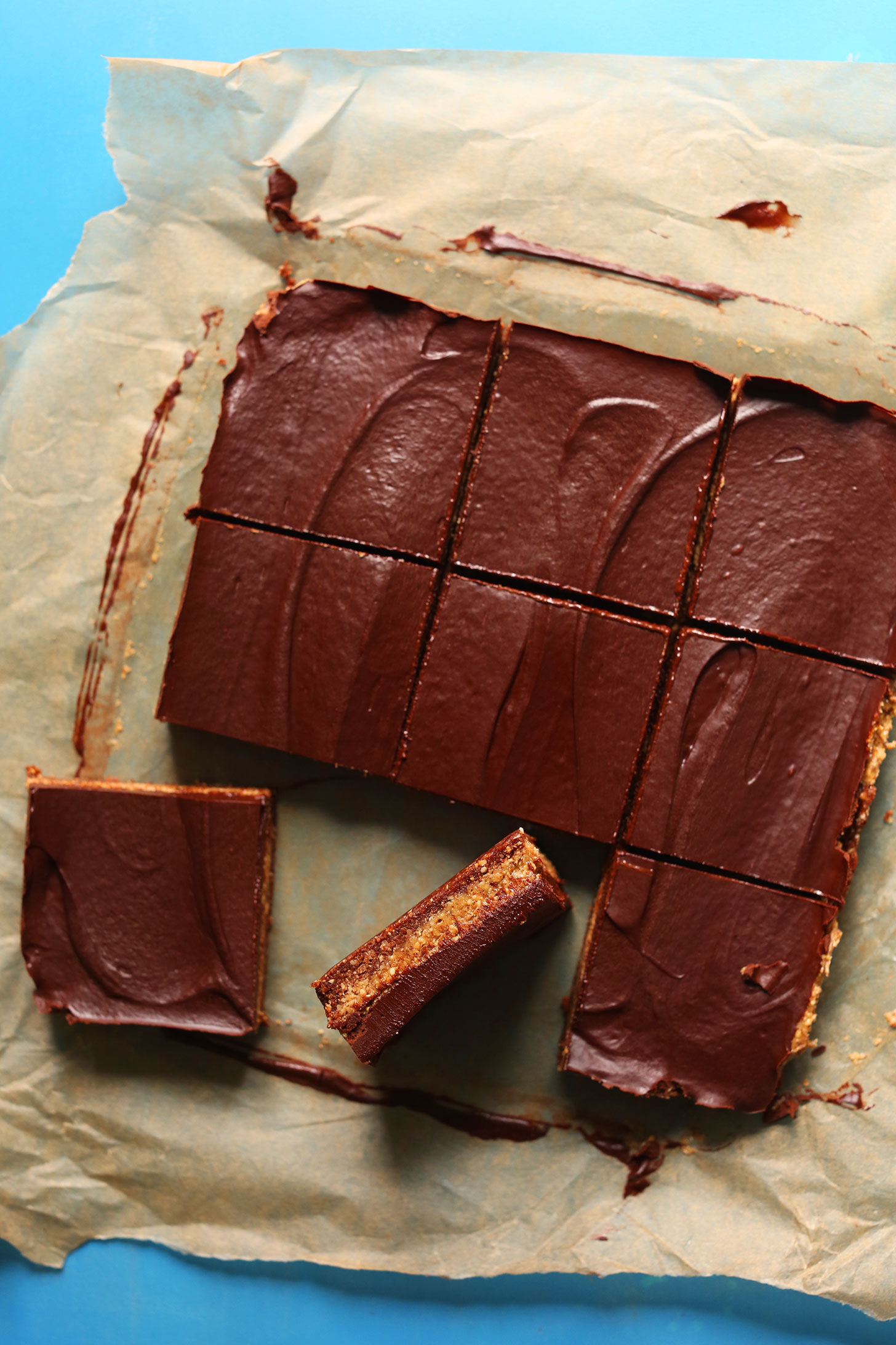 Parchment paper with squares of homemade gluten-free vegan Almond Butter Cup Bars