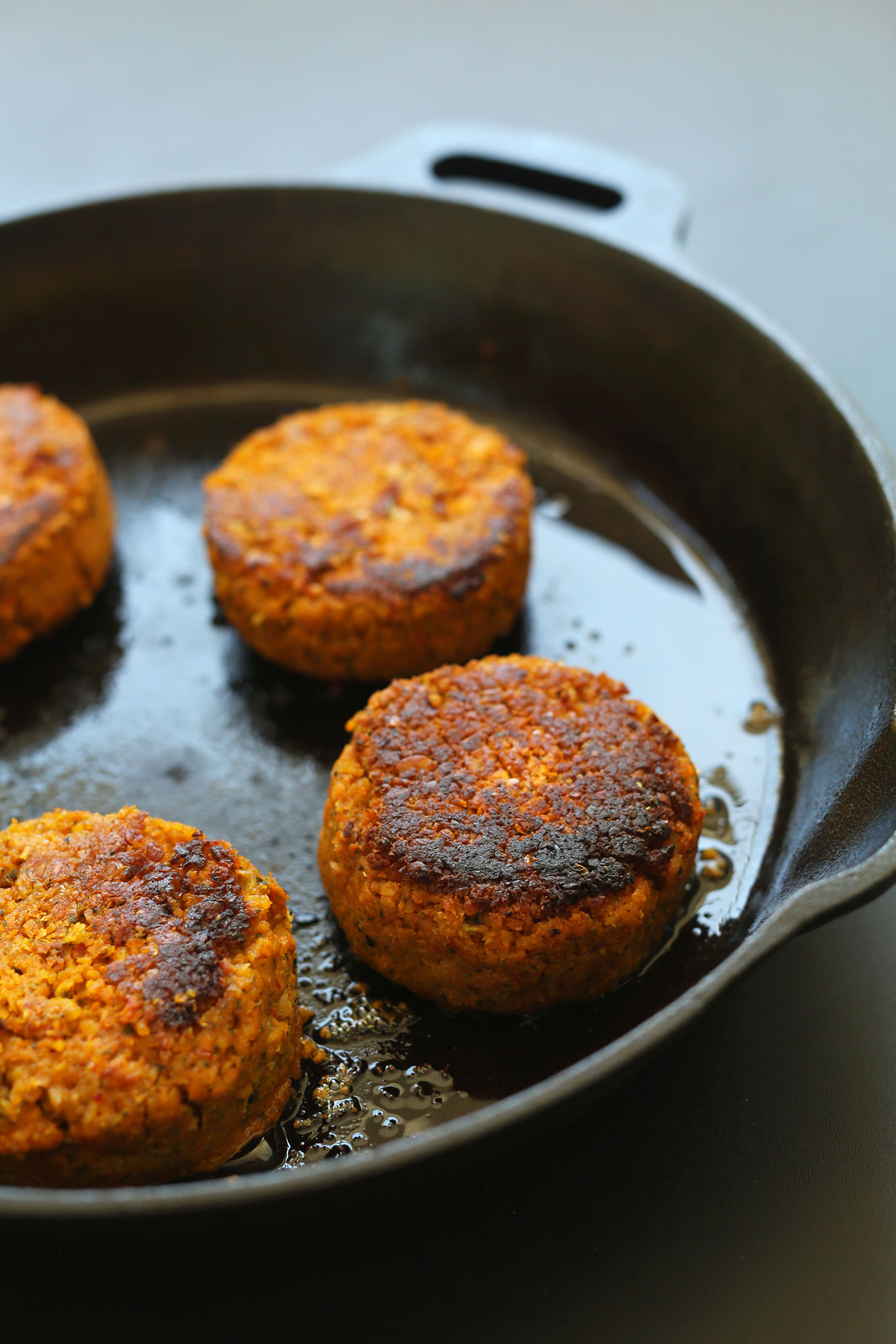 Cooking gluten-free vegan chickpea burgers in a cast-iron skillet