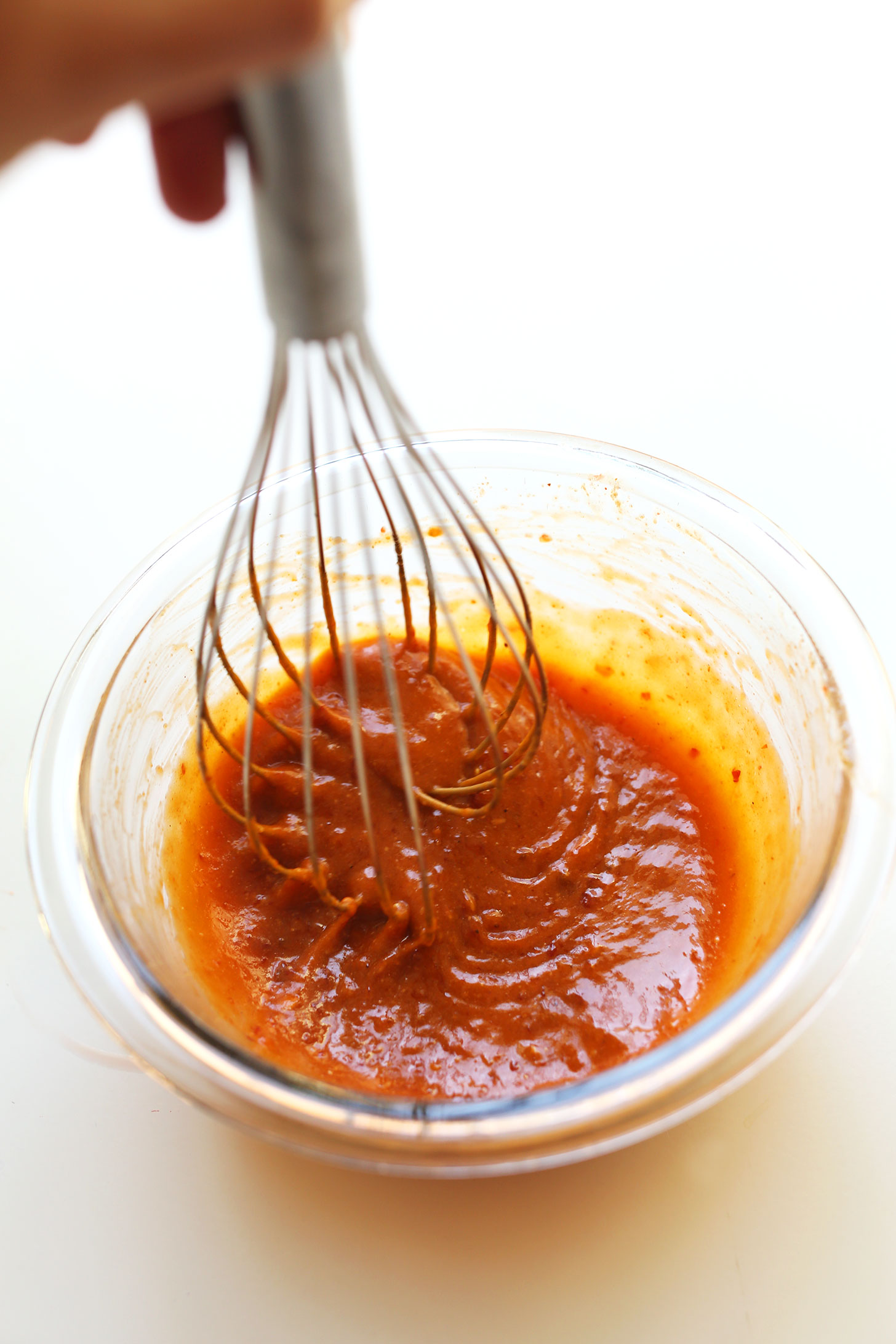 cashew sesame chili dressing being whisked in a glass bowl