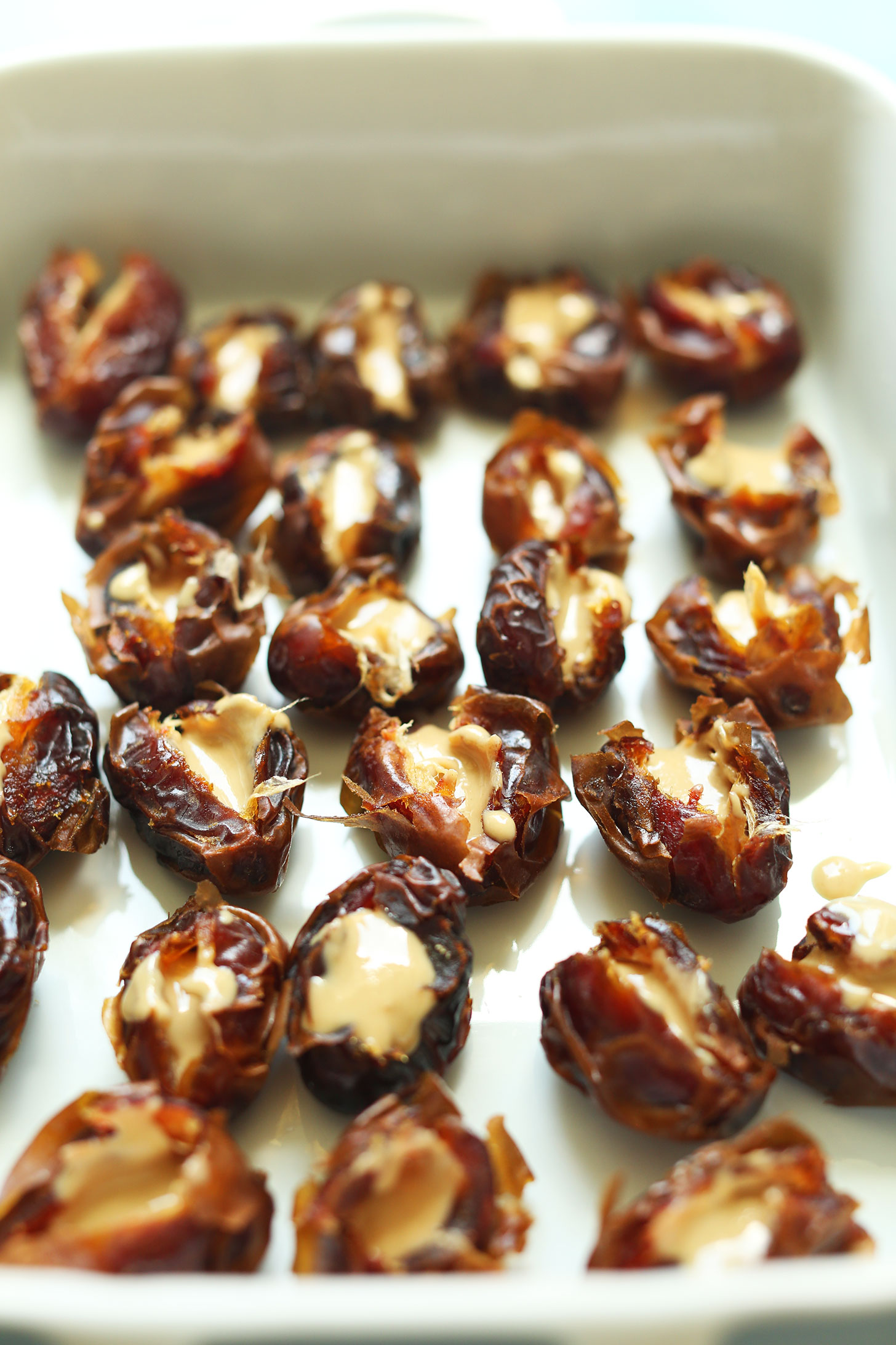 Ceramic baking dish with halved dates with tahini in the middle