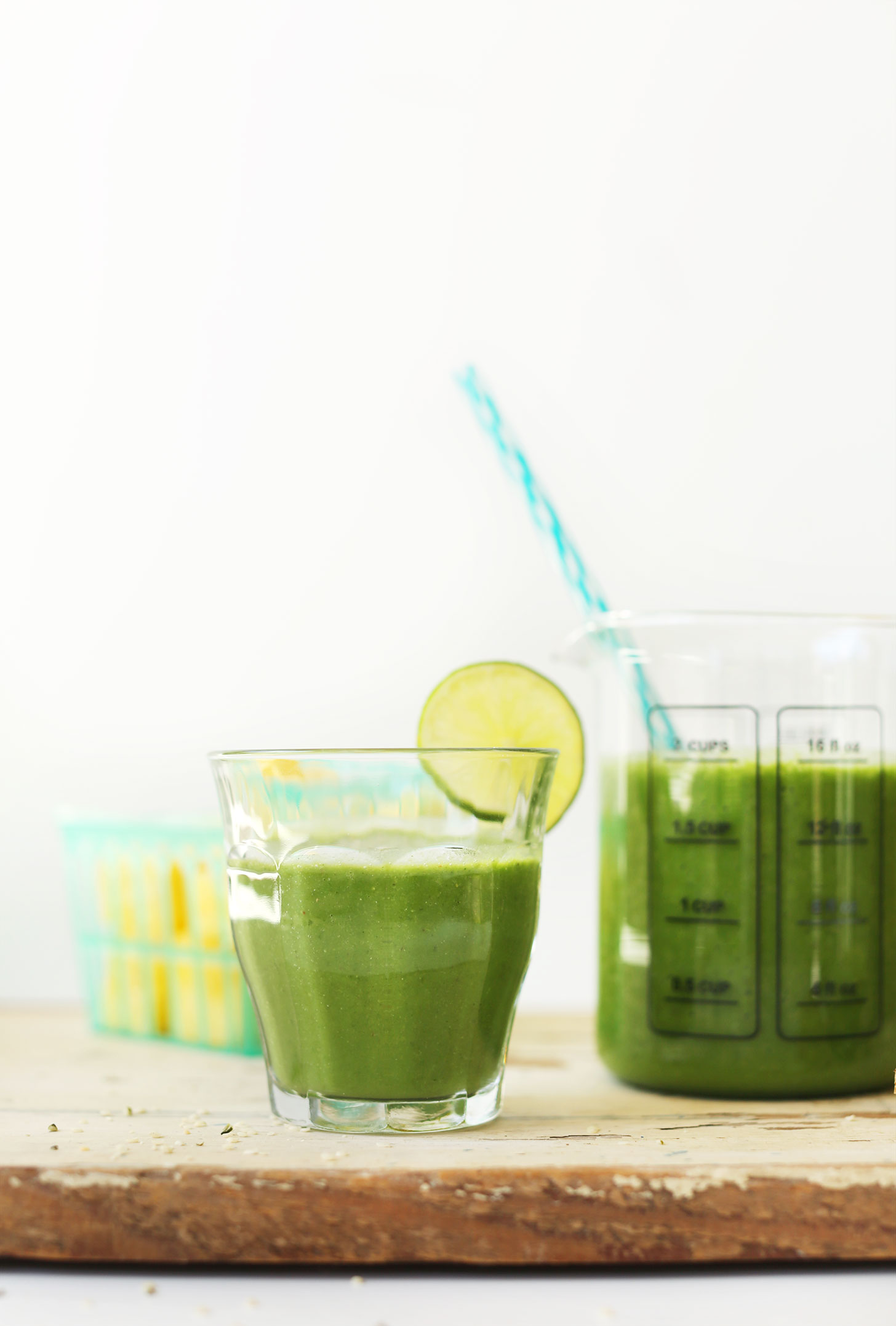 Serving glass filled with Ginger Colada Green Smoothie with a slice of lime on the rim