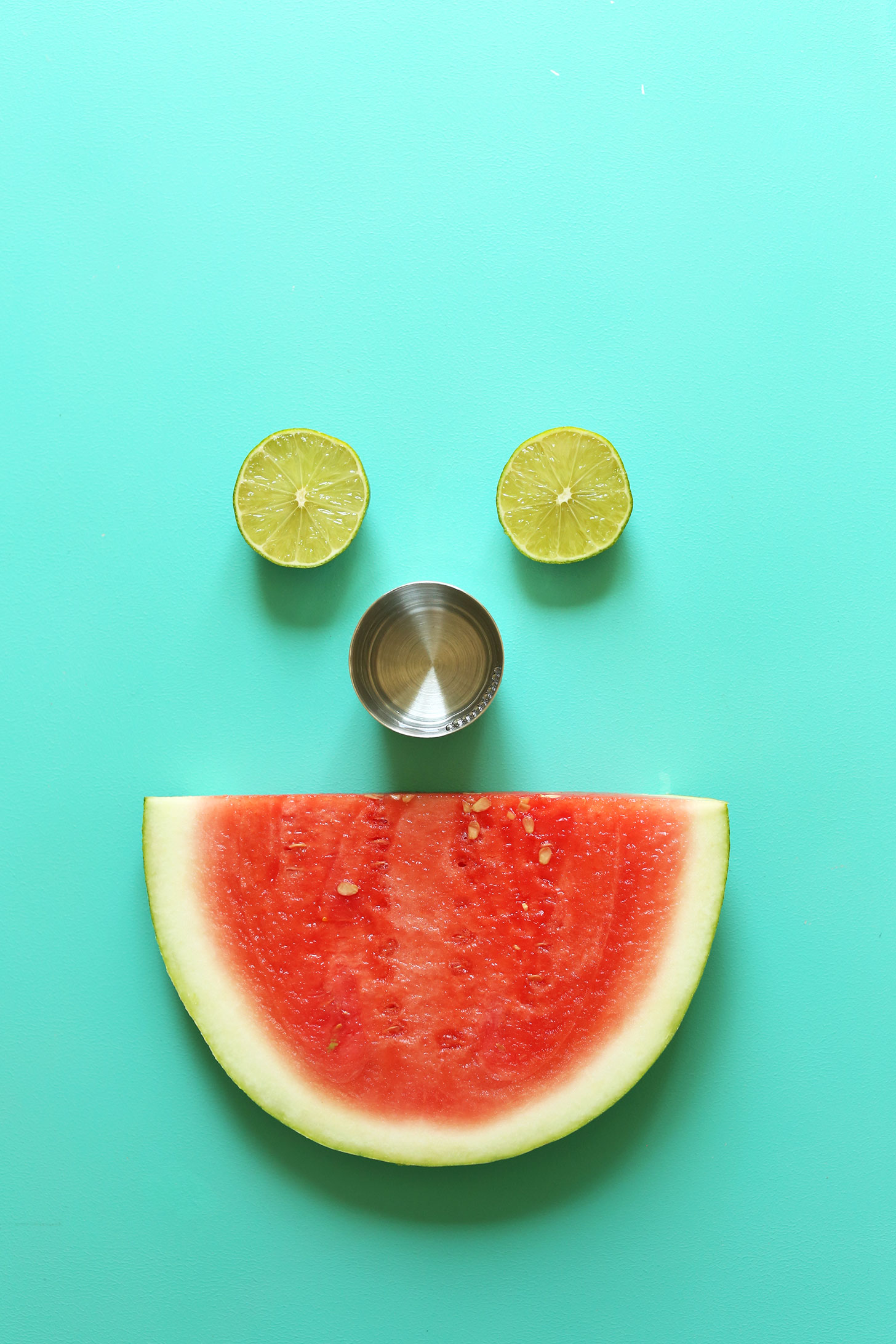 Limes, tequila, and watermelon arranged as a smiley face for Watermelon Margaritas