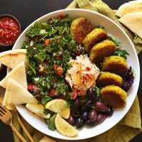 Ultimate Mediterranean Bowl of vegan falafel, pita, tabbouleh, hummus, olives, and lemon slices