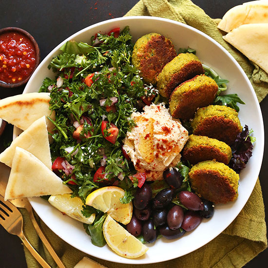 Ultimate Mediterranean Bowl of vegan falafel, pita, tabbouleh, hummus, olives, and lemon slices