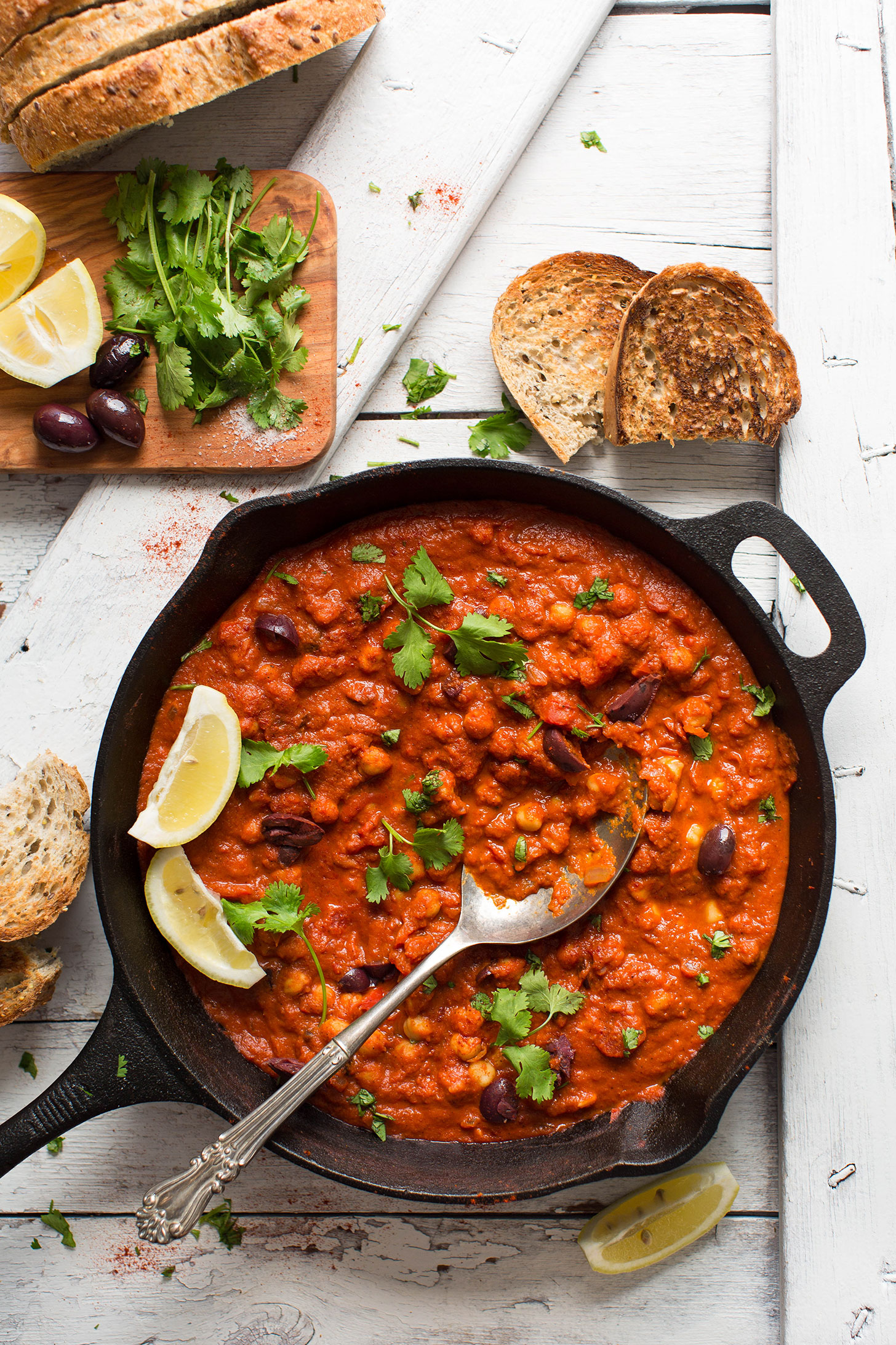 Cast-iron skillet filled with our gluten-free vegan Chickpea Shakshuka recipe served with crunchy bread
