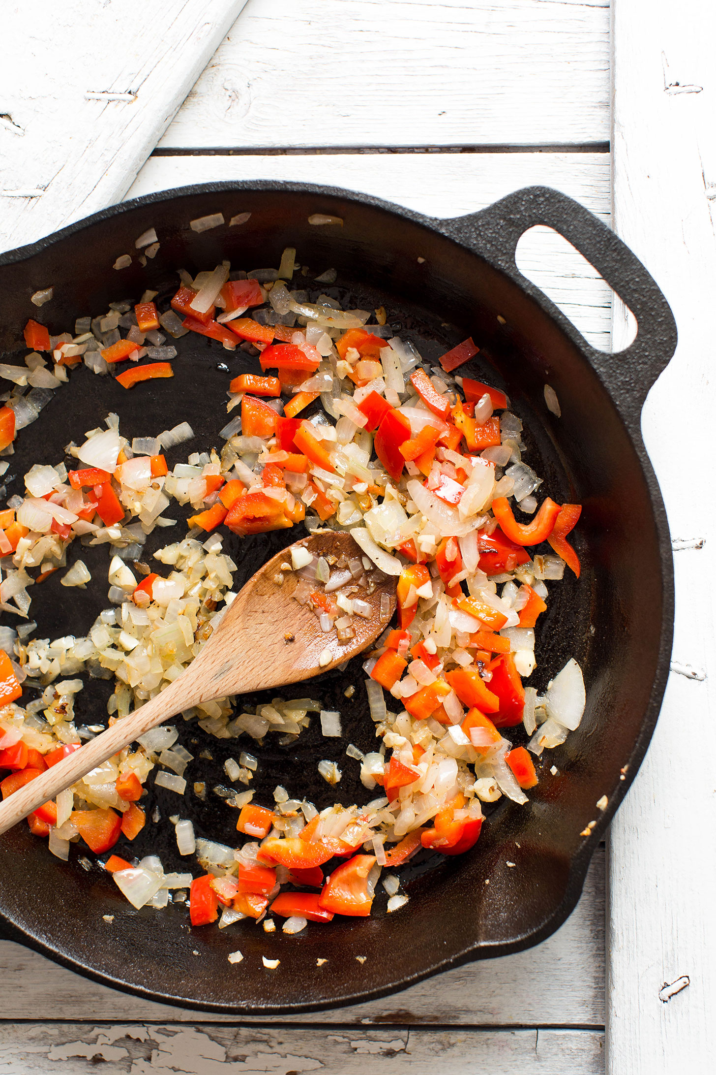 Sautéing onion, bell pepper, and garlic in a cast-iron skillet 