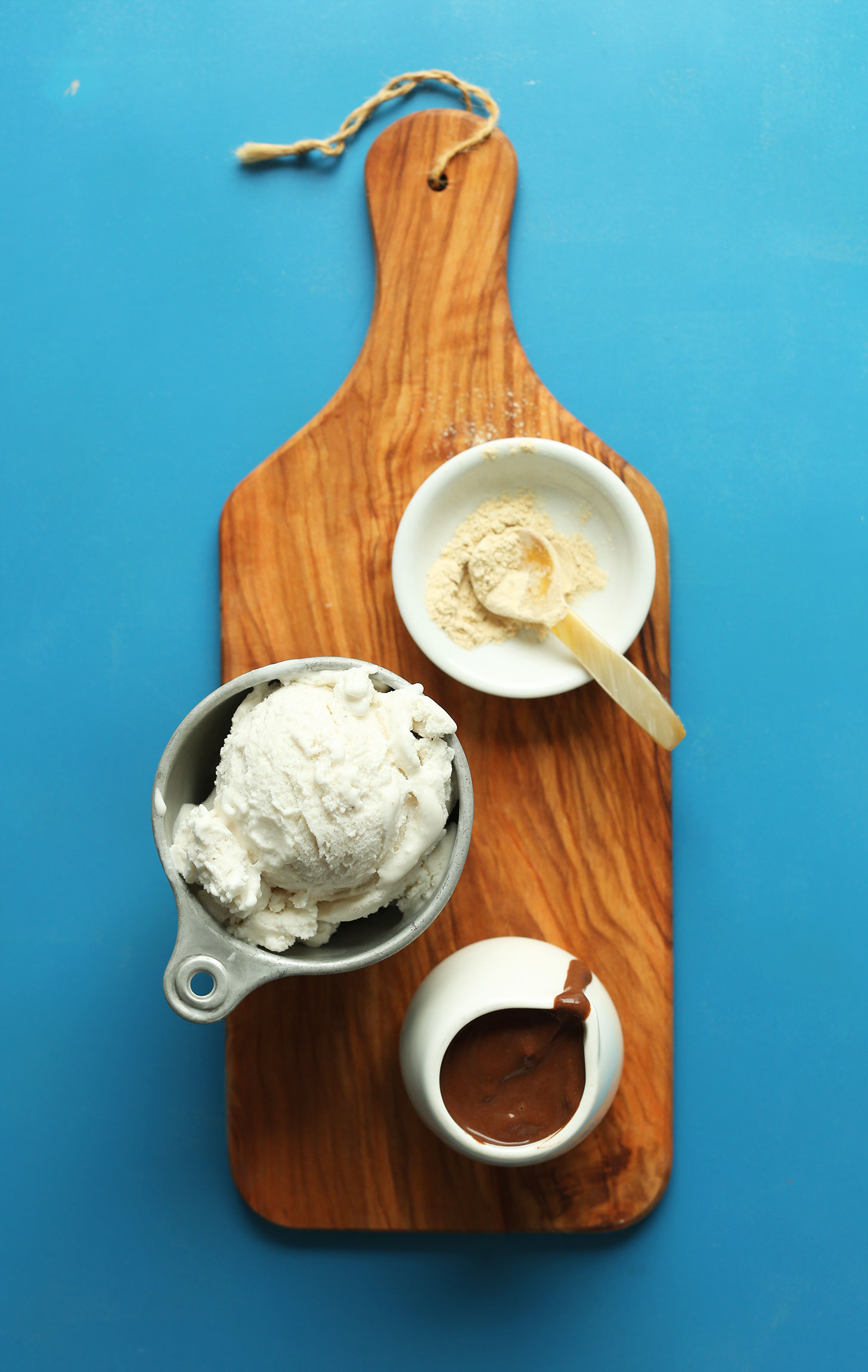 Wood cutting board with maca, vegan ice cream, and chocolate sauce for making a Chocolate Vegan Malt