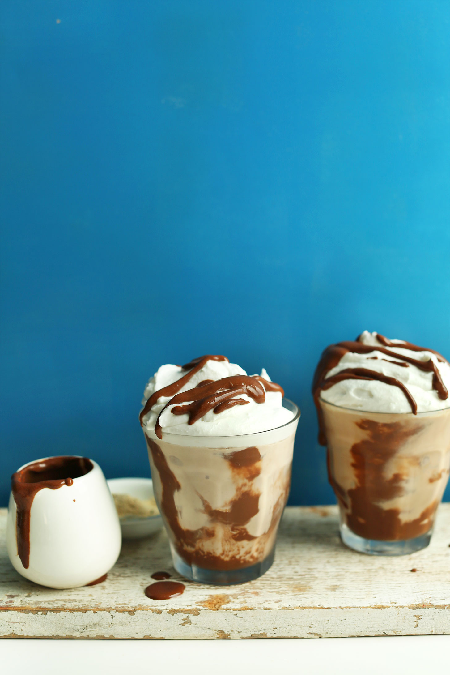 Two glasses of our gluten-free vegan Chocolate Malt drizzled with chocolate sauce