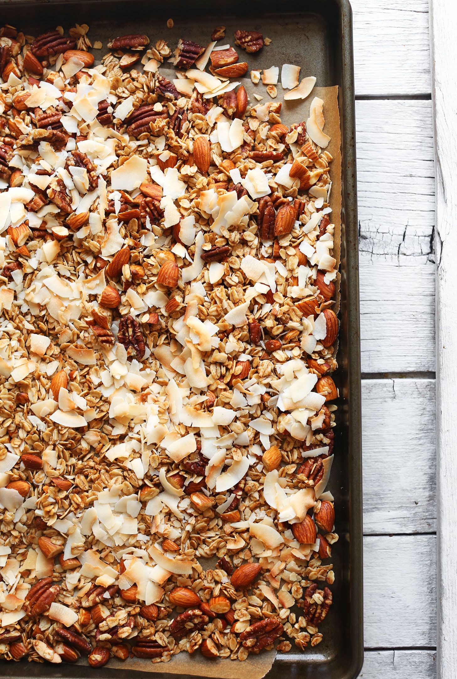 Parchment-lined baking sheet with freshly baked homemade Coconut Strawberry Granola