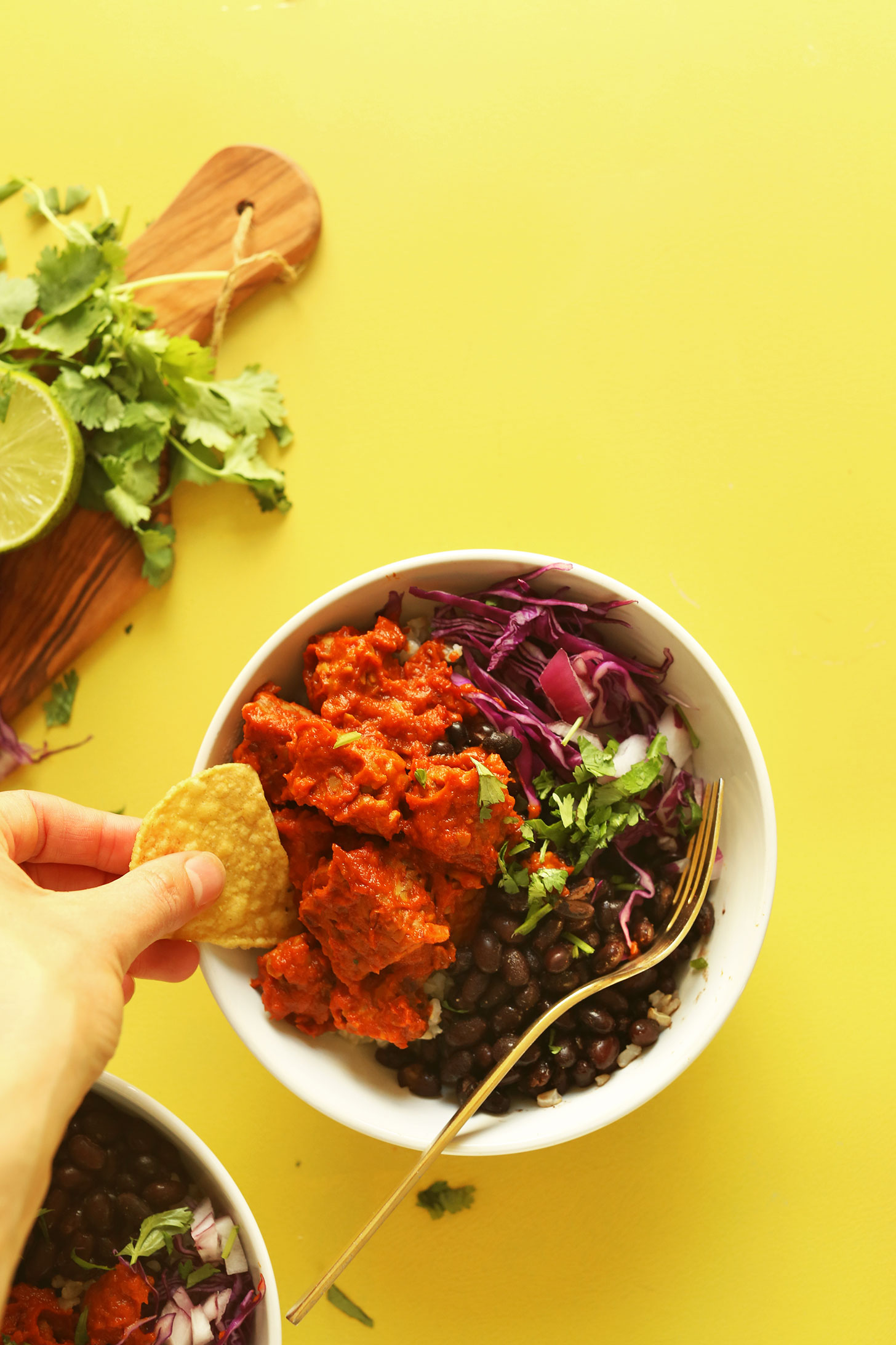 Dipping a tortilla chip into our gluten-free vegan Smoky Tempeh Burrito Bowl