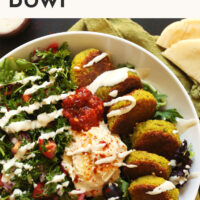 Mediterranean bowl with falafel, hummus, olives, parsley salad, and tahini sauce