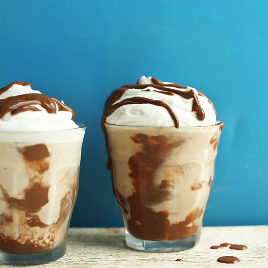 Two glasses of Vegan Chocolate Malt topped with coconut whip and chocolate syrup