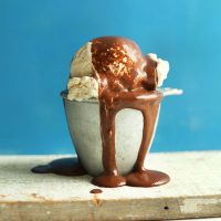 Measuring cup filled with scoops of ice cream dripping with homemade Vegan Chocolate Syrup