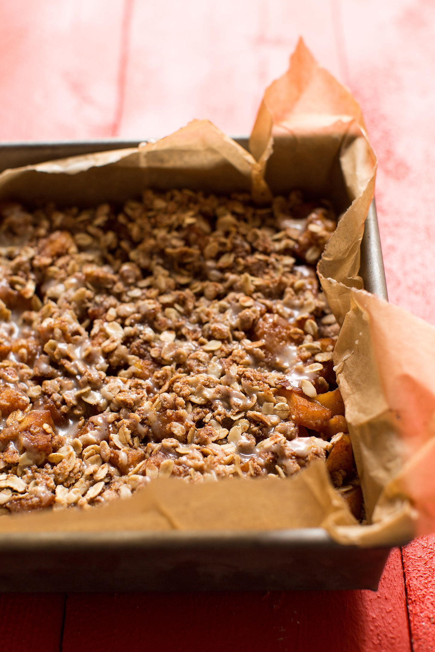 Freshly baked gluten-free vegan Apple Pie Crumble Bars in a parchment-lined baking pan