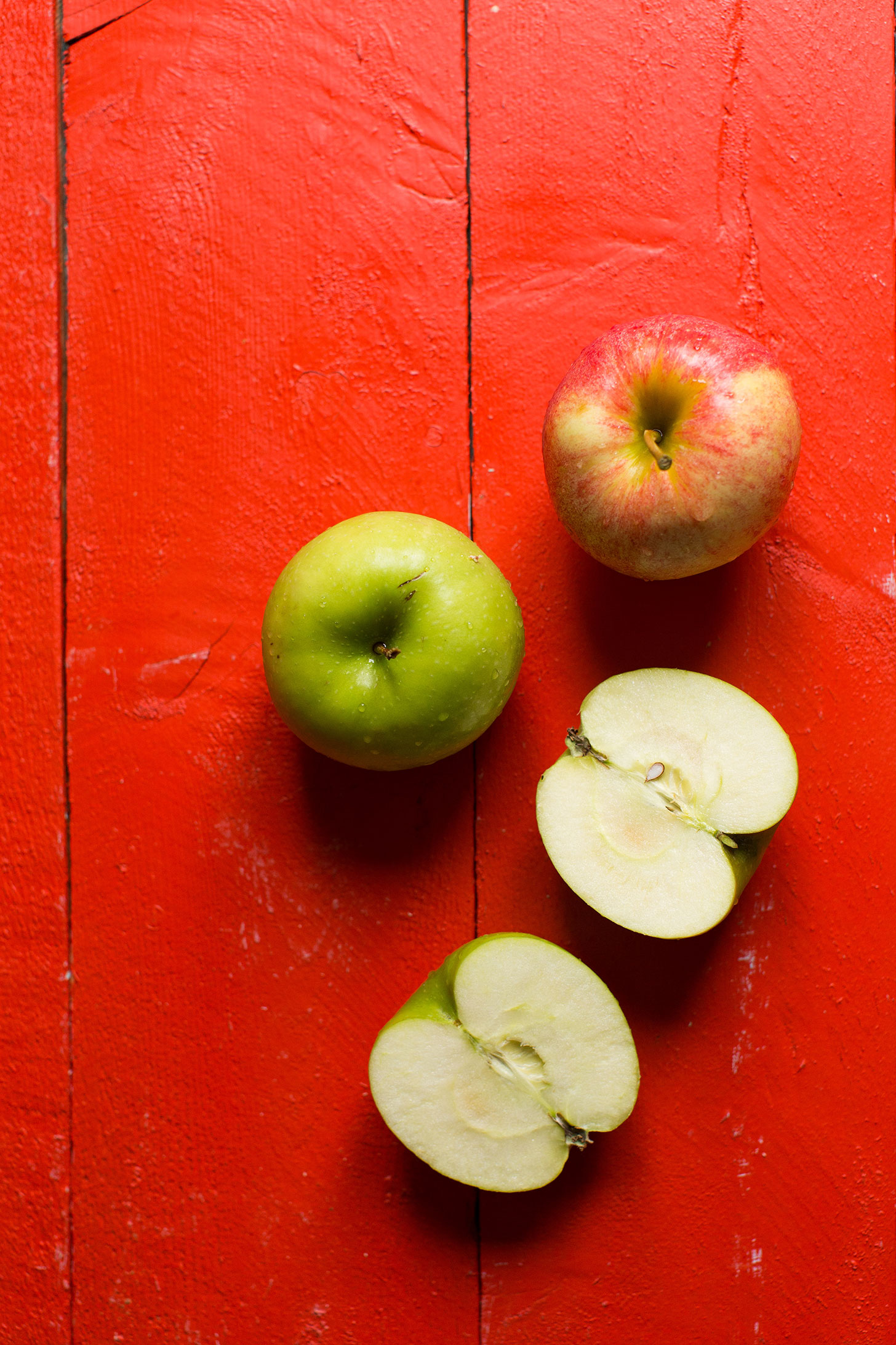 Fresh apples on a red background for a gluten-free vegan apple pie crumble bars recipe