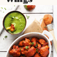 Overhead shot of a bowl of spicy red curry cauliflower wings and a bowl of dipping sauce