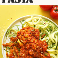 Plate of zucchini noodles topped with vegan lentil bolognese sauce with text above that says 30-minute